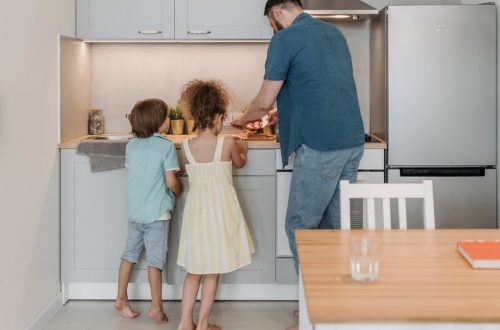 Father and children cooking together in a modern kitchen, enjoying family time.