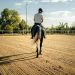 A person rides a horse in a sand arena.